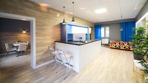 Eine moderne Küche mit einer zentralen Kochinsel, ein Essbereich mit Tisch und Stühlen sowie ein farbenfrohes Sofa.