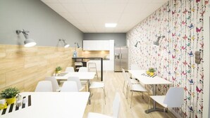 Ein moderner Arbeitsraum mit weißen Möbeln, einer Küchenzeile und Wandpapier mit Schmetterlingsmuster.