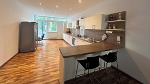 A modern kitchen with wooden flooring, a built-in bar area, and a view of the outdoors through large windows. - Luxury loft in Bayreuth Central&Exclusiv (Bayreuth)