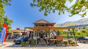 A building with a covered entrance, outdoor seating, and a mountain backdrop. - Shiroka Stays 3 in Shkod r (Shkodër)