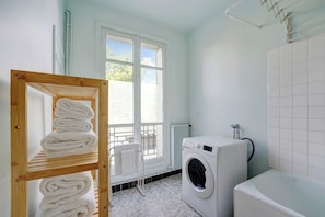 A laundry room with a washing machine, a drying rack, and a window with a view. - Elegant Apartment 1br/4p - Paris 15/montparnasse (Paris)