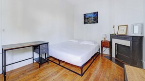 A bedroom with a bed, a desk, a dresser, a fireplace, and a painting on the wall. - Elegant Apartment 1br/4p - Paris 15/montparnasse (Paris)