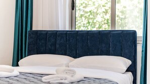 A neatly made bed with white pillows and a grey quilt, a blue headboard, and teal curtains. - Shiroka Stays 2 in Shkod r (Shkodër)