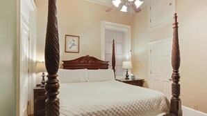 Un lit à baldaquin avec une couvre-lit matelassé, une tête de lit en bois et des tables de chevet avec des lampes.
