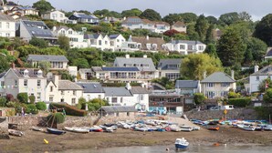 A coastal town with houses on a hillside and a marina with boats.