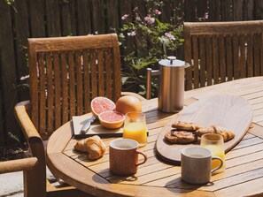 A wooden table with breakfast items including a croissant, orange juice, and a coffee mug. - The Porthole (Plymouth)