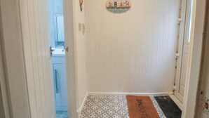 Un pasillo con un felpudo, un cartel que dice 'Everything is better than the beach', y una puerta que da al baño.