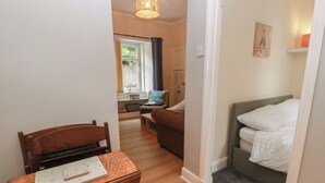 Una habitación compacta con una mesa de madera, una cama y una pequeña zona de estar.