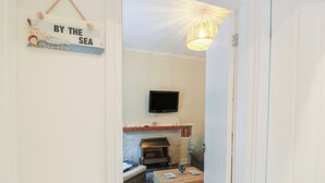 Una sala de estar acogedora con televisor, chimenea y un cartel que dice "BY THE SEA".