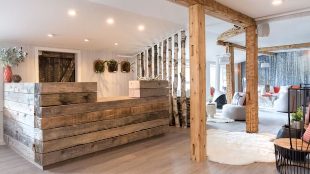 A wooden reception desk with a modern interior, including a white wall and a large window. - Rustic-Chic Double Room Perfect for Skiing Adventures Near Rentals (Stowe)