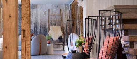 Une pièce chaleureuse avec un plafond en bois, un canapé et un fauteuil au design original, caractérisé par une structure en fil de fer.