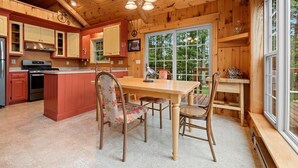 A wooden cabin kitchen with a central island, built-in cabinets, and a large window. - Private beach house in charming Pound on a clear, sandy full rec lake (Pound)