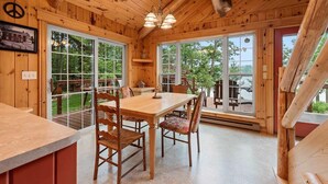 A wooden interior with a dining table and chairs, large windows, and a ceiling with a deer head sculpture. - Private beach house in charming Pound on a clear, sandy full rec lake (Pound)