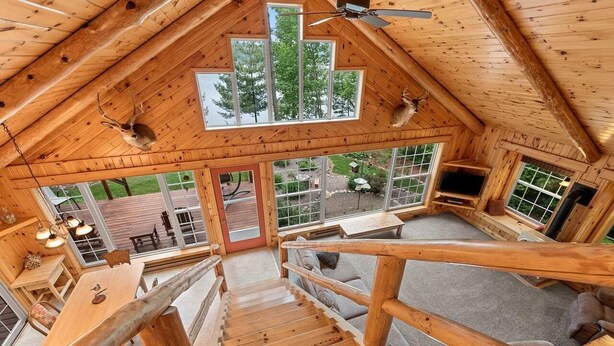 A wooden cabin with a loft bedroom, a dining area, and a TV. - Private beach house in charming Pound on a clear, sandy full rec lake (Pound)