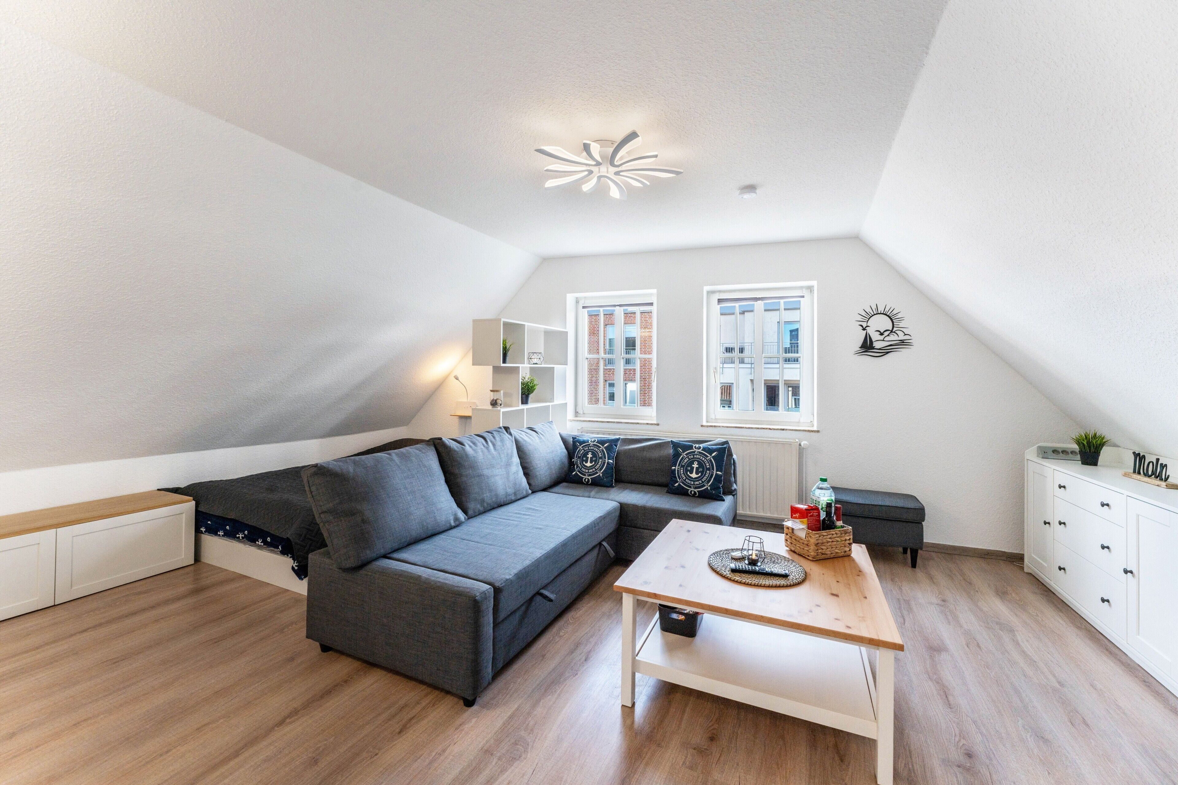 Un dormitorio tipo loft moderno con una cama grande, un escritorio y un ventanal con vistas a un edificio.