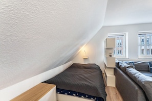 Et soveværelse med seng, sofa, et natbord, en lampe og et vindue.