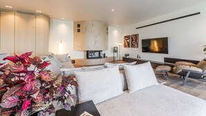 Una sala de estar moderna con un sofá, una mesa de centro y un televisor montado en la pared.
