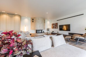 A modern living room with a sofa, a coffee table, and a TV mounted on the wall.