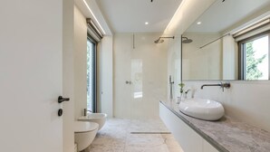 Un baño moderno con un espejo grande, un lavabo y un inodoro.