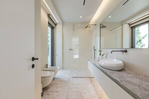 A modern bathroom with a large mirror, a sink, and a toilet.