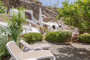 Un bâtiment blanc avec des fenêtres en arc, et une chaise blanche au premier plan.