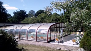 Ein Poolbereich mit Glasfassade, Liegestühlen und freiem Blick auf den Pool.