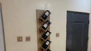 A room with a wooden wine rack holding several bottles, a door, and a small stool. - Zircon- Comfortable 1 bedroom  apartment in GRA Ikeja (Lagos)