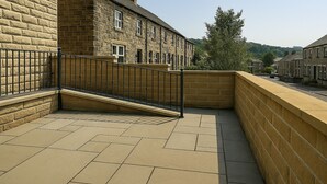 A courtyard with a stone wall, a metal railing, and a tiled floor. - The Signature Residence (Newsome)