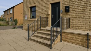 A building with a stone facade, a black door, and a staircase with metal railings. - The Signature Residence (Newsome)