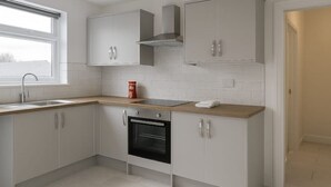 A modern kitchen with white cabinets, a wooden countertop, a built-in oven, and a window providing natural light.