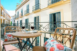 A balcony with wicker furniture, a table, and two wine glasses.