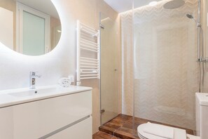 A modern bathroom with a glass shower enclosure, a white sink, and a mirror. - Spectacular Apartment in Santa Cruz . Aire I (Seville)