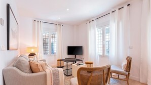 Een moderne woonkamer met een bank, een houten stoel, een televisie en een bijzettafeltje.