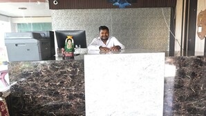 A reception desk with a marble counter, a computer, and a small statue.