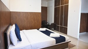 A hotel room with a bed, a wardrobe, and a desk with a chair.