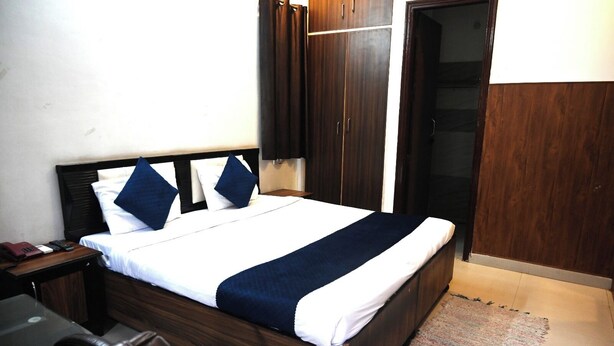 A neatly made bed with a white and navy blue bedspread, a wooden headboard, and a dark wooden wardrobe.