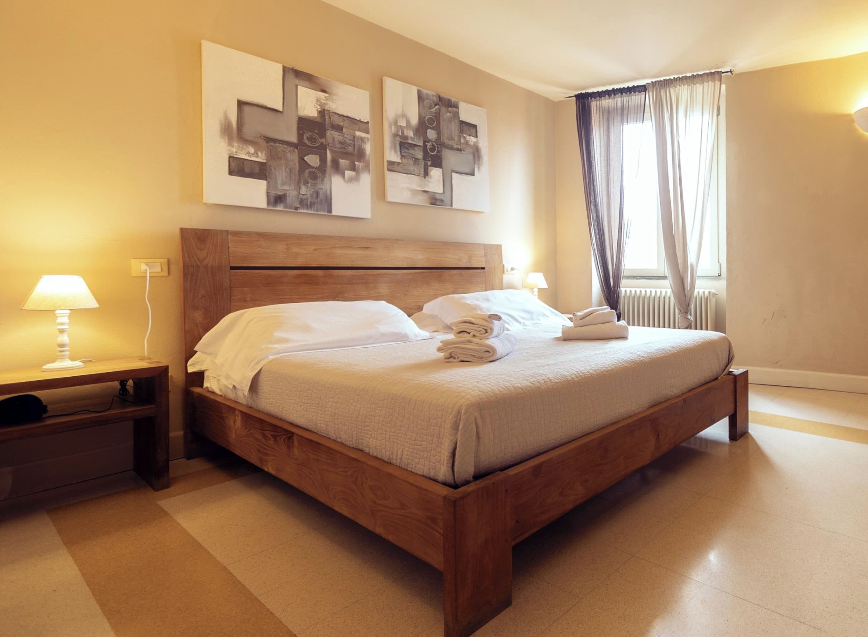 A neatly made bed with white linens, a wooden headboard, and a bedside table with a lamp.