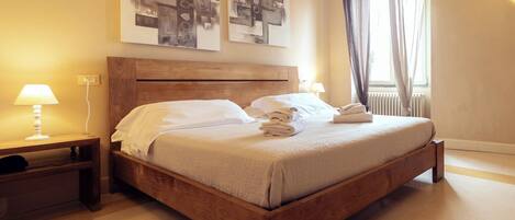 A neatly made bed with white linens, a wooden headboard, and a bedside table with a lamp.