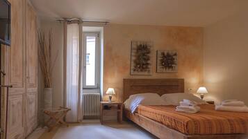 Une chambre à coucher avec un lit, deux lampes de chevet, un radiateur et une fenêtre avec des rideaux.