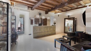 Amplia sala de estar con techo de madera, un mostrador de recepción y un área de descanso con sofá y mesa de centro.