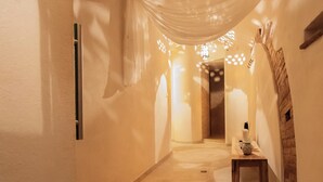 A hallway with a wooden bench, a wall-mounted light fixture, and a door at the end.