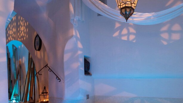 Zona de spa con jacuzzi, mobiliario de madera y una lámpara colgante.