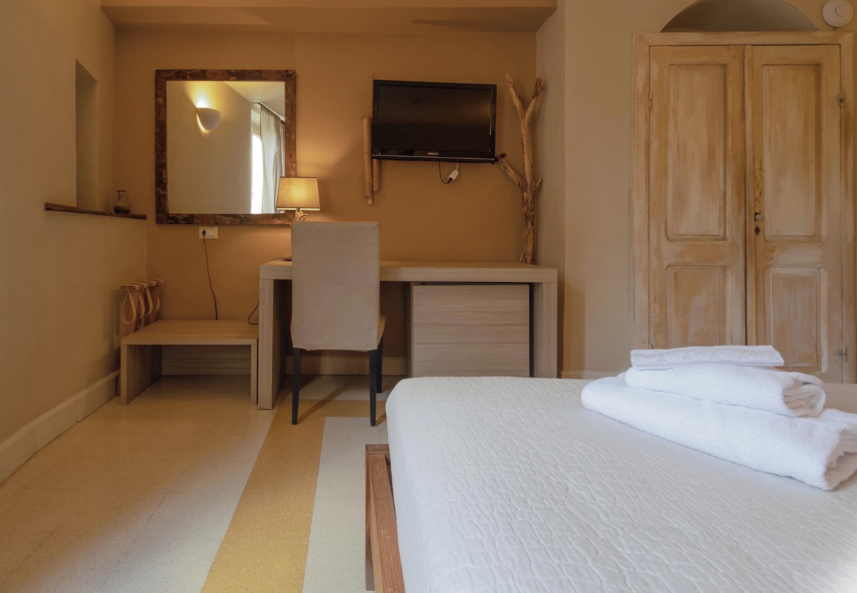 Une chambre d’hôtel équipée d’un lit, d’un bureau, d’une chaise, d’un miroir et d’une télévision.