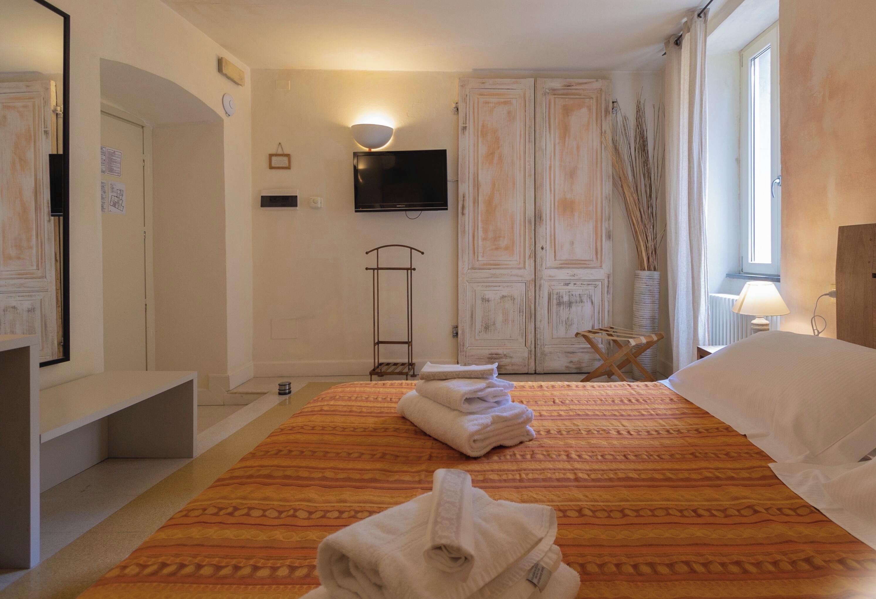 Une chambre d’hôtel avec un lit, une télévision, une armoire et une fenêtre.