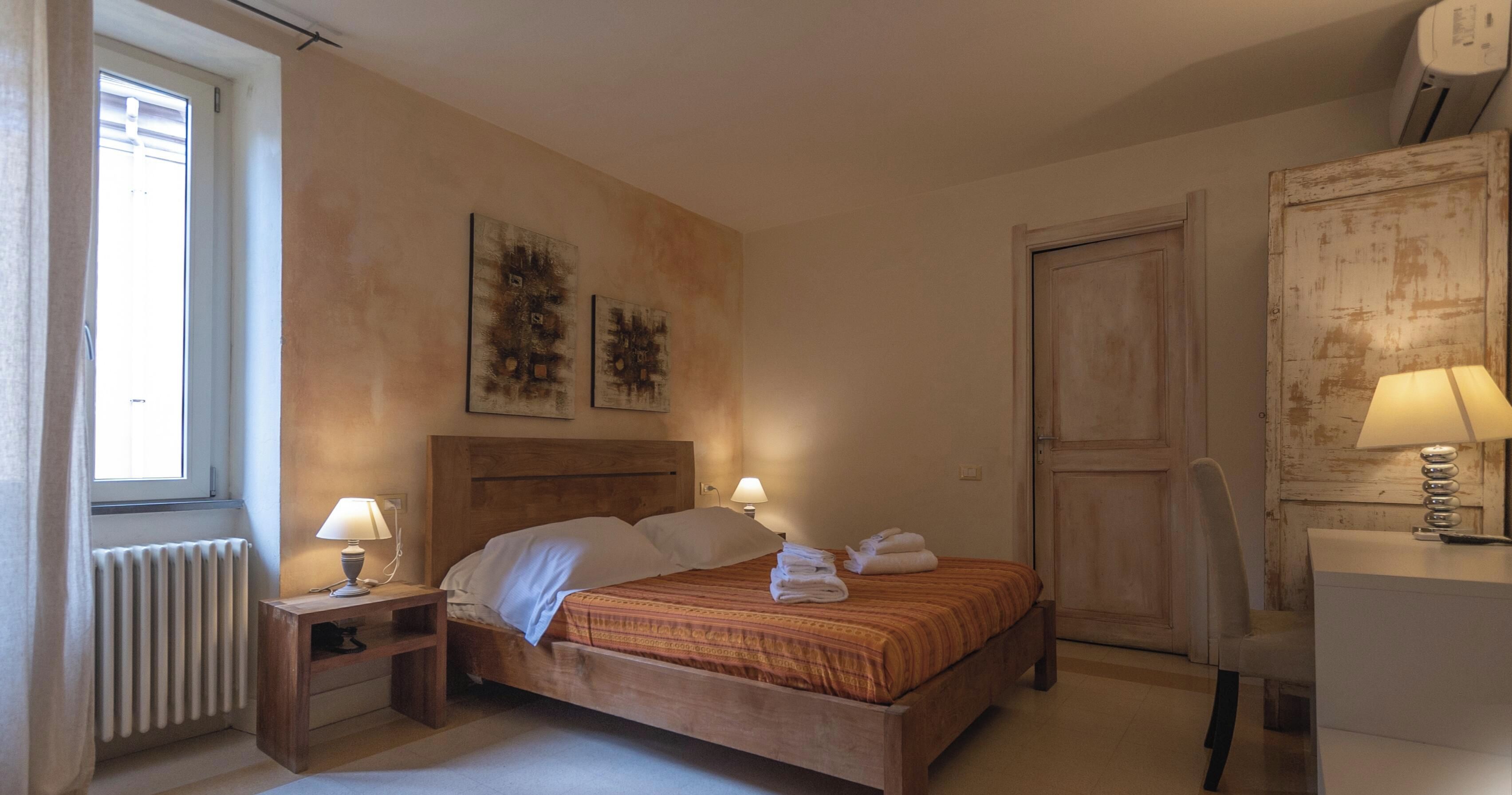 Una camera da letto con un letto in legno, due lampade sui comodini, un termosifone e una porta.