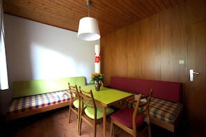 A room with a wooden ceiling, a green table, wooden chairs, a bench with a plaid cushion, and a vase with flowers. - Apartment '3' with Shared Terrace, Balcony and Wi-Fi (Dachsberg (Südschwarzwald))