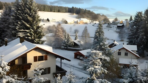 Ein schneebedecktes Dorf mit traditionellen Häusern, einem klaren Himmel und einem entfernten Berg.