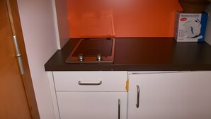 Une cuisine équipée d’une cuisinière, de placards et d’une boîte posée sur le plan de travail.