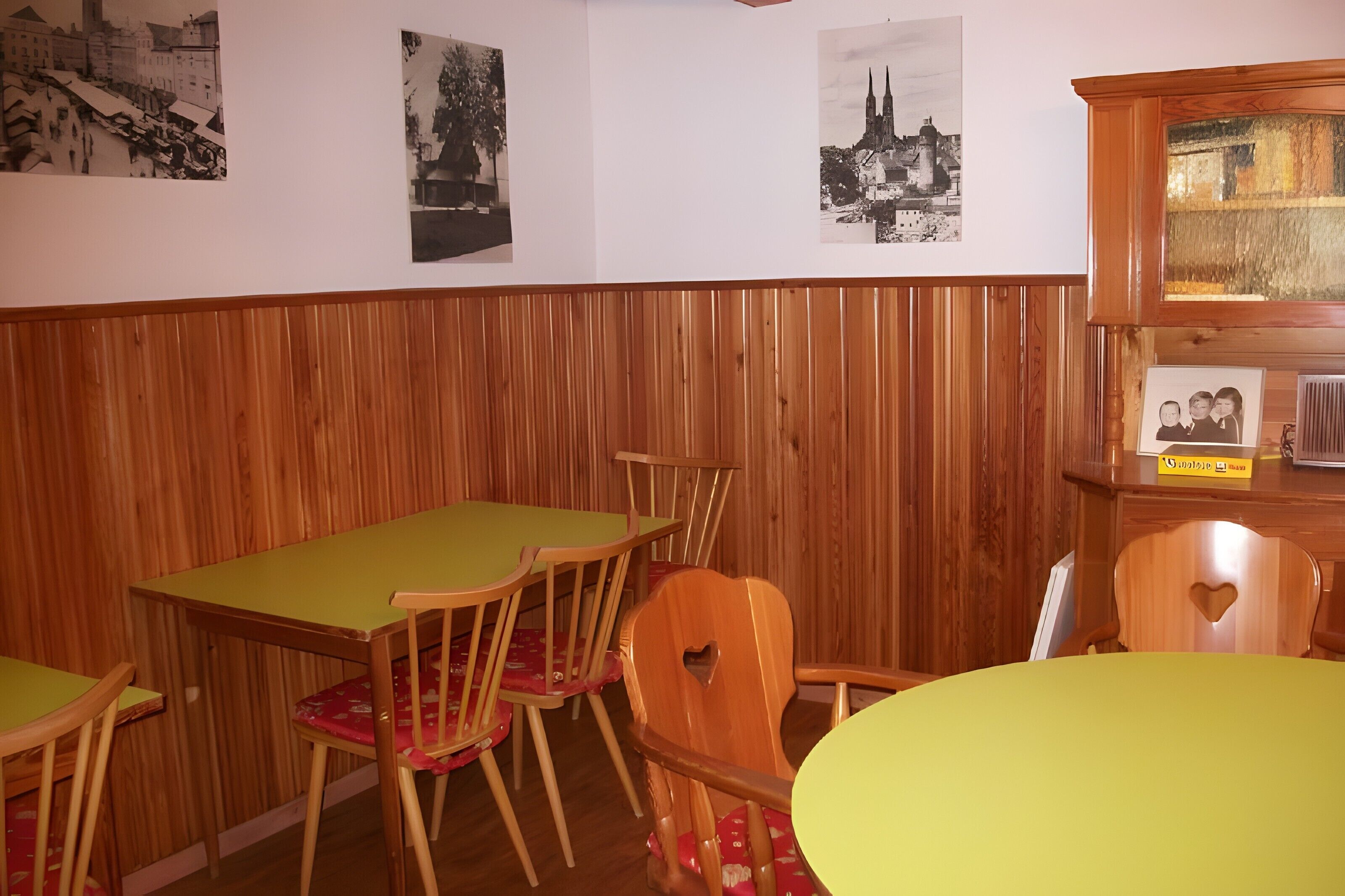 Un comedor con paredes de paneles de madera, una mesa verde y sillas con respaldo en forma de corazón.