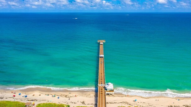 Une longue jetée qui s’avance dans l’océan, avec une plage à son extrémité.